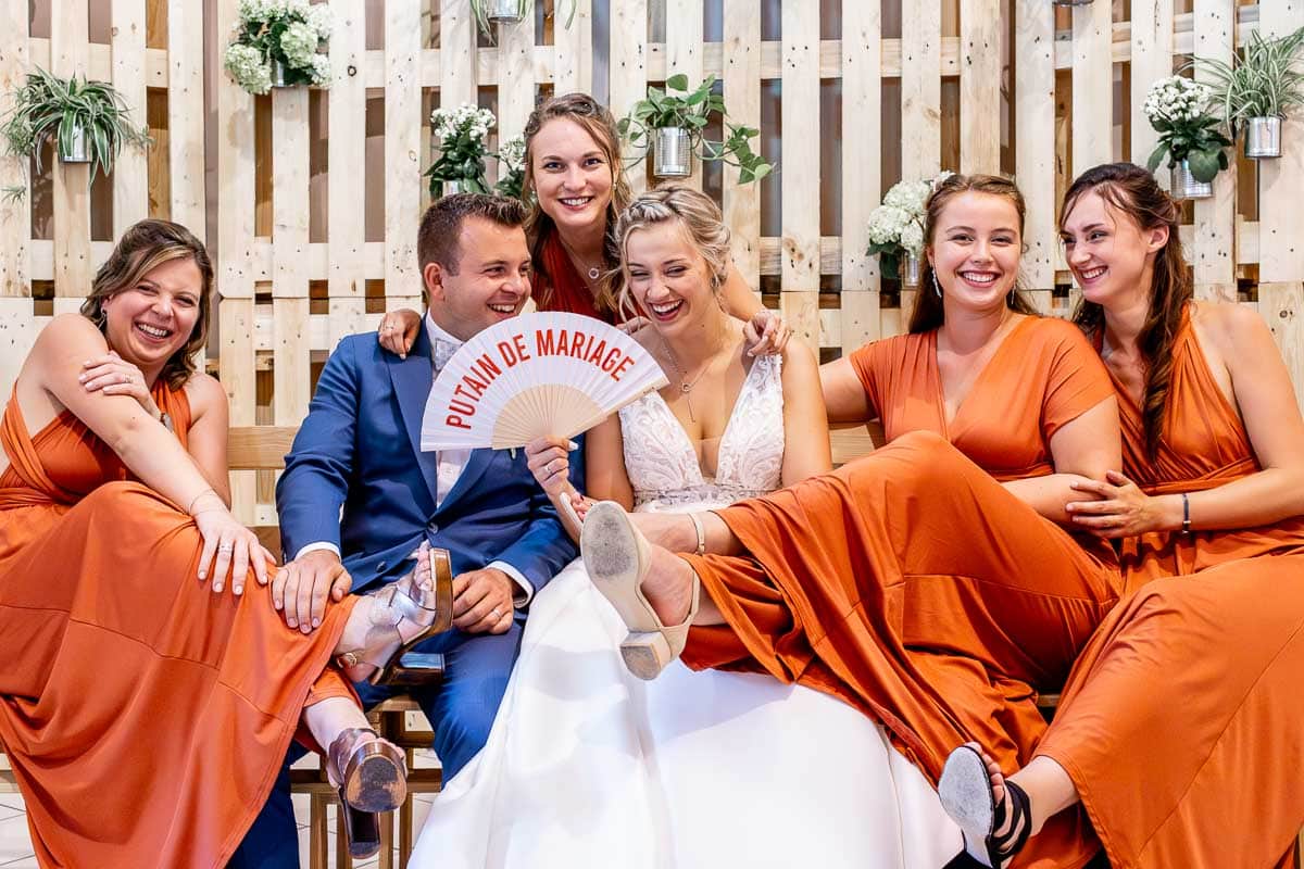 Couple de mariés d’Amiens entourés de leurs demoiselles d’honneur qui sont assis sur un banc en bois