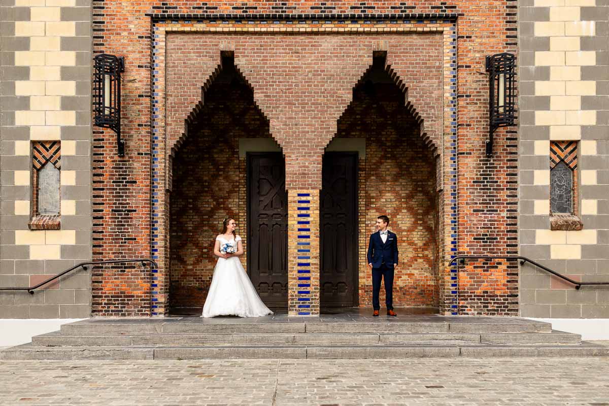 Couple de mariés habitant à Lille qui se regardent devant la porte d’une église