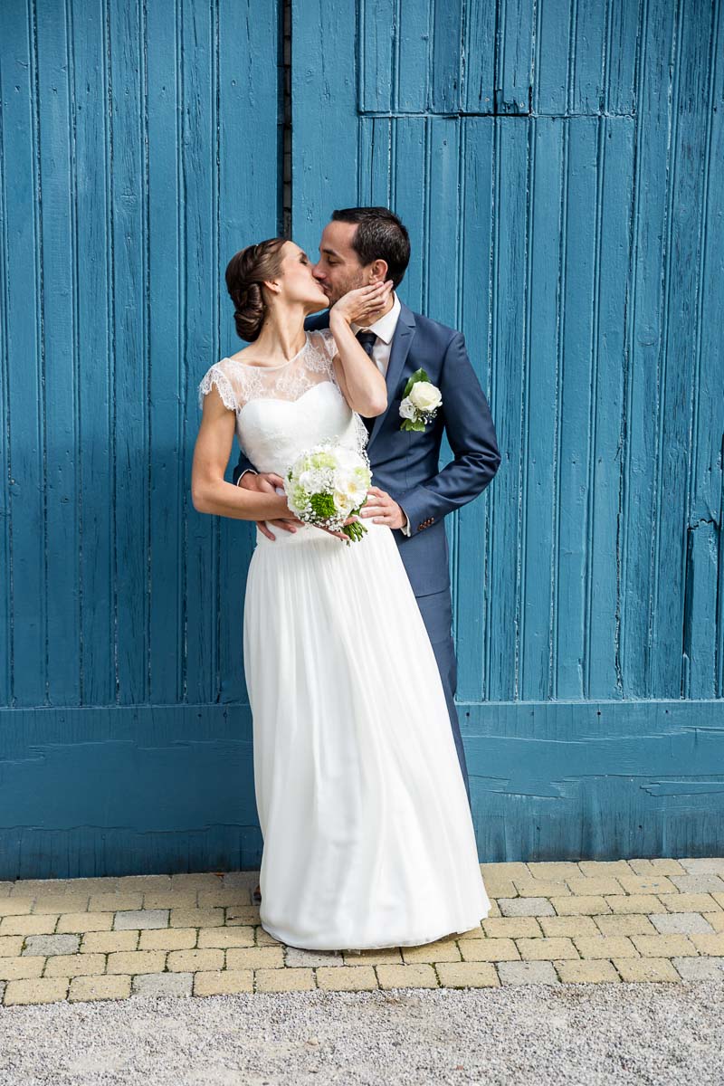 portrait de mariés qui s’embrassent devant une grande porte lors de la séance de couple du photographe de mariage olivier cousson photographe