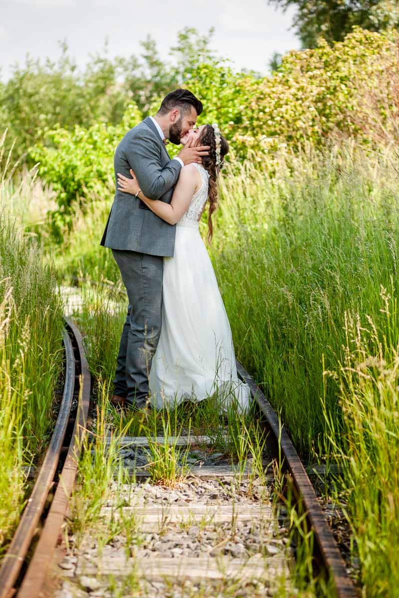 Mariés qui s’embrassent sur un chemin de fer abandonné lors d’une séance de couple à Lille