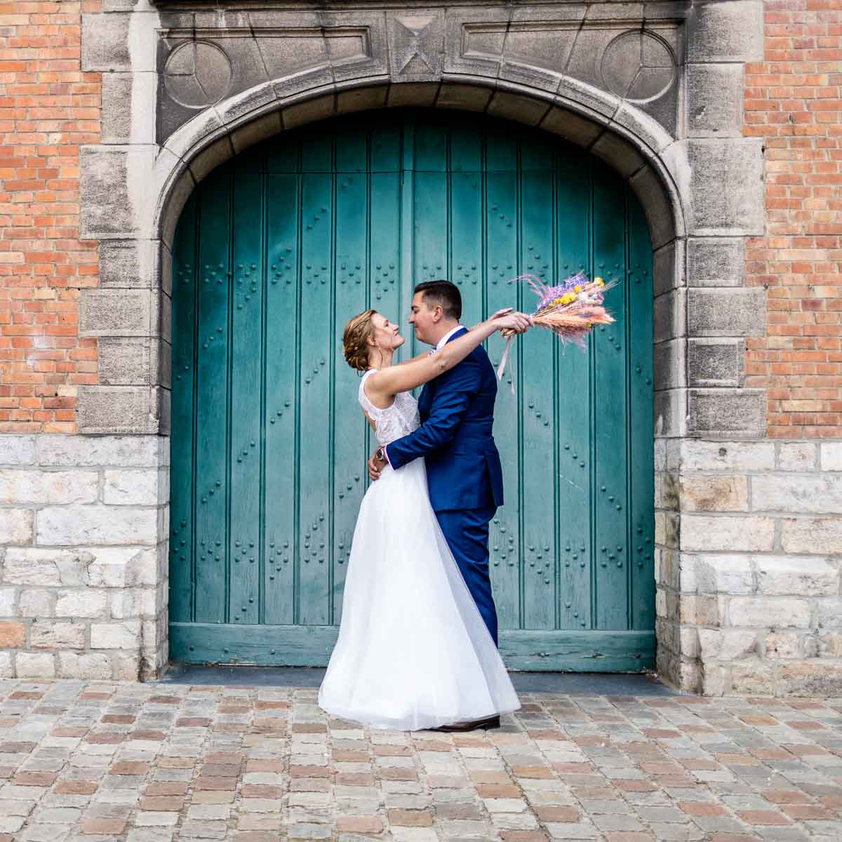 Mariés devant une grande porte verte lors d’une séance de couple dans le nord