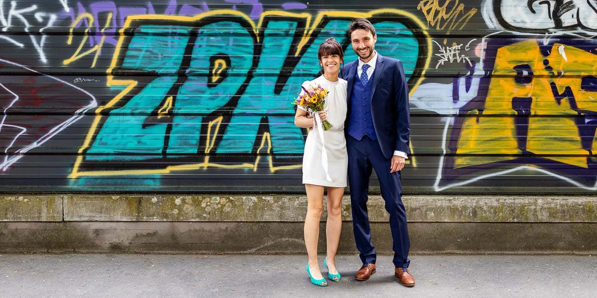 Couple de mariés devant un mur remplis de tags graffitis lors d’une prestation du photographe de mariage Olivier Cousson