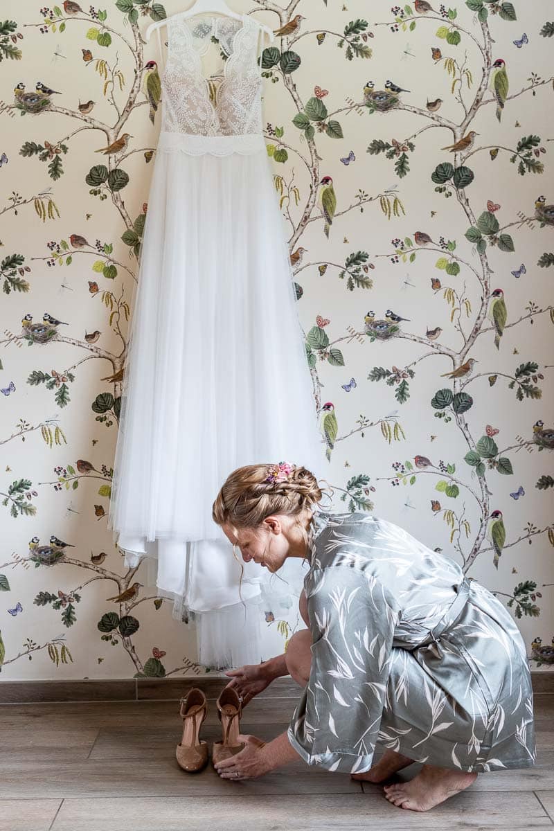 Mariée naturelle en peignoir qui pose ses chaussures sous sa robe de mariée dans la métropole lilloise